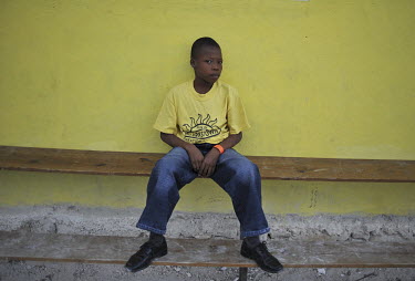 A boy in the Ebenezer Foundation Orphanage in Croix Besbouquets sits alone on a bench. His orange bracelet indicates that he is new to the orphanage, which is run by the Global Orphan Project. Many ch...