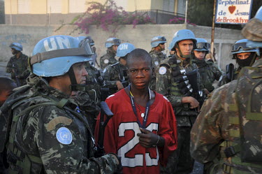 A young man stands beside a group of Brazilian UN Minustah troops while waiting for food distribution in Cite Soleil, twelve days after an earthquake hit the country. To guarantee the safety of the ai...