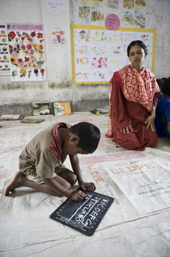 A child writes the English alphabet on his slate at school in Patuakhali district.