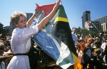 A white woman burns the new South African flag at a right-wing demonstration in Pretoria. It became the official flag of South Africa in April 1994 to represent the move from apartheid to multiracial...