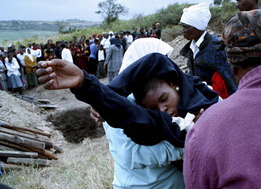 A mourner collapses at the graveside during the funeral of three brothers. The three, aged 18, 19 and 25, were killed by gunmen who burst into their house. One of the brothers was a member of the Afri...