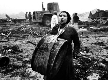 A resident of Bloekombos squatter camp wails and beats a drum as white council workers, guarded by riot police, bulldoze about 35 shacks during a dawn raid in the dying days of apartheid.