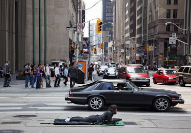 A homeless man lies on a street in central Toronto.