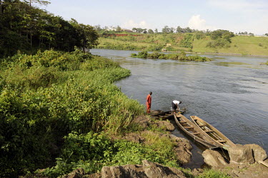 Elliot Onyuthfua (in red) fixes his boat on the banks of the river Nile in Lower Naaur village near Jinja. Elliot does not own his own land and he and his family depend entirely on the Nile for their...
