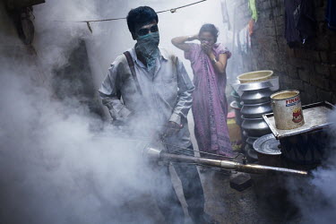 In Calcutta, a man sprays fog to kill mosquitoes in order to protect people from malaria.
