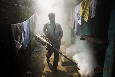 In Calcutta, a man sprays fog to kill mosquitoes in order to protect people from malaria.