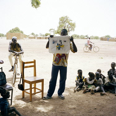 A man teaches children about malaria in a remote village in Namentenga.