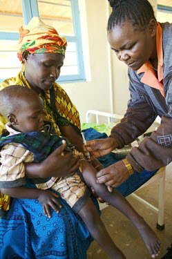 A nurse gives an injection to a young boy who has malaria.