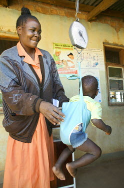 A nurse weighs a small boy who has malaria at a health centre.