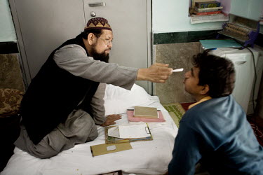 A mentally ill man endures an exorcism by Mohammed Omar Faridi, a pir at the Shareef Dargah in New Delhi. Delhi is typical of many Indian cities in that it has very few trained psychiatrists and many...