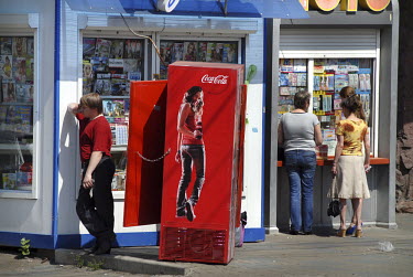A man talks on a mobile phone near an advert for Coca Cola outside a shop in the city centre of Krasnoyarsk.