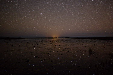 A fishing camp fire burns into the vast sky over Bangweulu where hundreds of stars reflect in the still waters.
