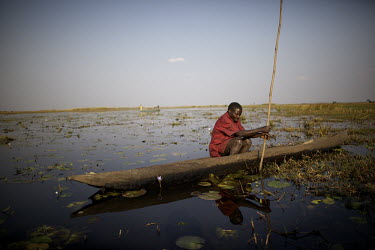 A fisherman sits in a dugout canoe to travel which he uses to travel around Lake Bangweulu.