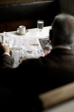 An elderly man reads a newspaper in the Indian coffee house, Baba Kharak Singh Marg. The coffee house dates back almost fifty years, first in central Connaught Place, then Janpath and now at the top o...