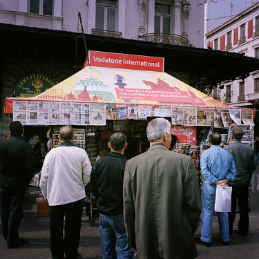 People reading the cover pages of newspapers and magazines at a newsagent kiosk in Omonia Square in the heart of theAthens.
