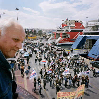 An old man watching a demonstration of Piraeus Port workers and the confederation of Greek workers during the financial crisis.