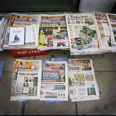 Newspapers and magazines displayed on the pavement, all running stories about the financial crisis.