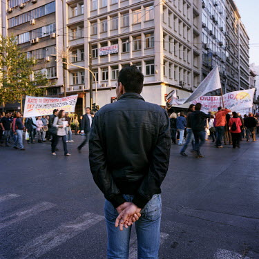 A man watching demonstrators as they walk from Omonia towards Syntagma square during the financial crisis.
