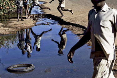 Children play around raw sewage as it flows through the streets of Bulawayo. Open sewers like this are largely responsible for the cholera epidemic that has struck the country.