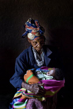 94 year old Golidem holds her one year old great grandson Nhkosina in a small hut in rural Zimbabwe.