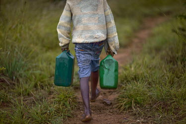 A seven year old orphan, whose parents died of AIDS and who is HIV positive himself, collects water from a nearby pool.