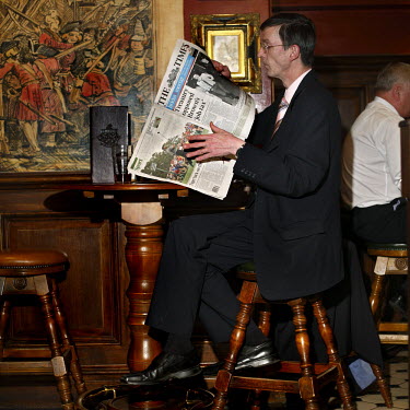 A man reading The Times newspaper during lunchtime at The Shooting Star pub in the City of London.