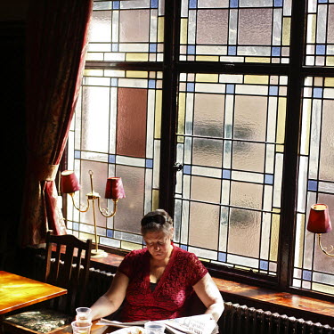 A woman reading a newspaper in The Globe pub on Baker Street, London.