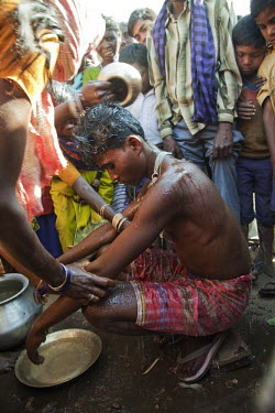 A groom is ritually cleansed by women from his bride's village prior to the wedding ceremony: One of the wedding traditions of the Santhal Adivasi tribal people.