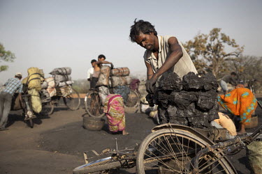 Men load their bicycles with coal at a small non-mechanized mine before undertaking a two-day trek to bring the coal to market. The work pays about 500 rupees (GBP 7.40) which is shared with their und...