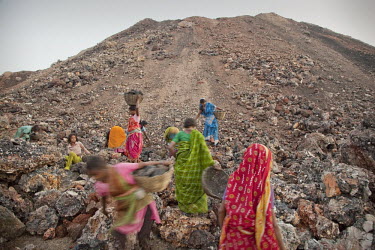 Women collect coal scraps from an overburden dump for a nearby open pit coal mine. Overburden is the fertile soil (formerly used for agriculture) that has to be removed to get at the coal underneath....