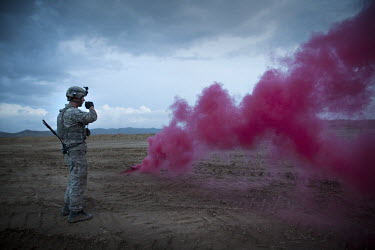 A smoke grenade signals to a medevac helicopter as US Army's SGT Smith, HQ Company 1-503rd Infantry, 173rd Airborne, talks on a radio on Jaghatu Combat Outpost. The medevac is for SPC Wade Slack, EOD...