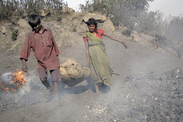 A man and woman carry a sack of coal collected from an illeagal mine between Hazaribag and Ranchi to be sold for a few Rupees in local markets. As mining spreads across Jharkhand and farming disappear...