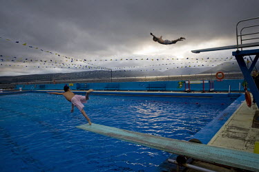 Children dive into Gourock outdoor swimming pool beside the Clyde estuary, near Glasgow.