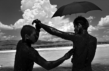 Men apply mineral rich black mud to each other to treat their skin at Lake Urmia, a salt lake in the province of West Azerbaijan, protecting themselves from the sun with an umbrella. The salt and mine...