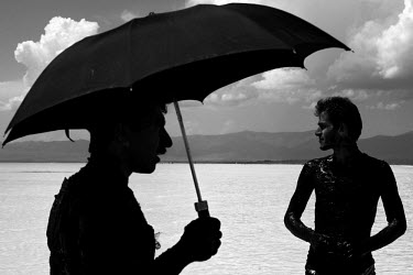 Men use mineral rich black mud to treat their skin at Lake Urmia, a salt lake in the province of West Azerbaijan, protecting themselves from the sun with an umbrella. The salt and mineral laden mud ar...