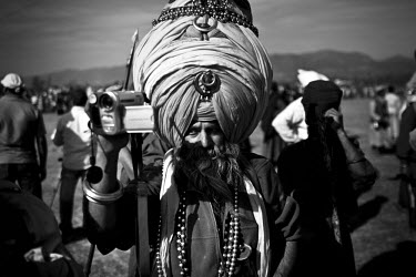 A Sikh man wearing a huge turban films events on a camcorder during the Hola Mohalla Festival. It takes place on the first day of the lunar month of Chet (March/April).