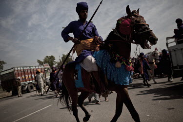 A man holding a lance rides an ornately decorated horse at the Hola Mohalla Festival. It takes place on the first day of the lunar month of Chet (March/April).