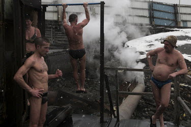 Men and women stand in the snow in their swimming outfits. They are preparing to go swimming in the river in Norilsk, a resource-rich city in Siberia above the Arctic Circle.