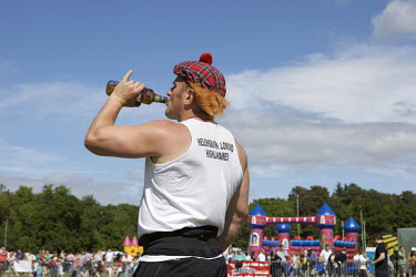 A competitor drinks from a bottle of whisky at the Helensburgh and Lomond Highland Games in Argyll.