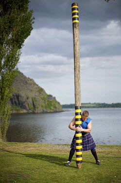 Neil Elliott wears a kilt as he holds a caber near his home in Dumbarton. He competes in over 40 Highland Games and heavyweight events across the world throughout the summer.