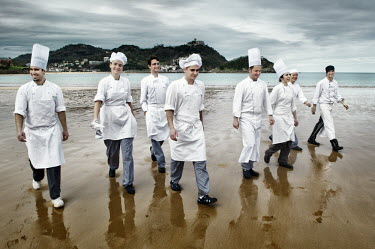 Chefs studying at Luis Irizar's cookery school walk on a beach in San Sebastian.