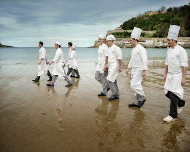 Chefs studying at Luis Irizar's cookery school walk on a beach in San Sebastian.