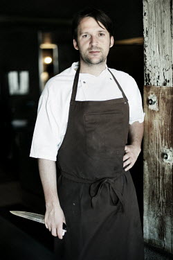 A portrait of chef Rene Redzepi holding a knife in the kitchen of his two Michelin star restaurant Noma, which was voted the best restaurant in the world in 2010.