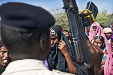 A soldier holds a gun as people queue to be treated at a clinic run by AMISOM (African Union Mission in Somalia). There has been an AU mission in Somalia since March 2007, part of an international eff...