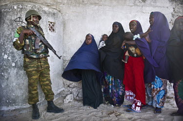 A Ugandan soldier holds a gun as women and children queue to be treated at a clinic run by AMISOM (African Union Mission in Somalia). There has been an AU mission in Somalia since March 2007, part of...
