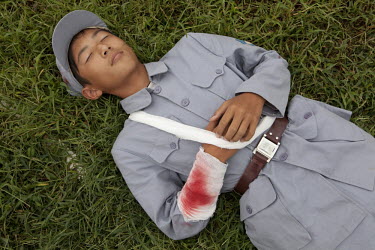 A competitor dressed in a PLA (People's Liberation Army) revolutionary era outfit lies 'wounded' on the 'battlefield' waiting to be picked up in the 'Rescue the Wounded Soldier' event of the Red Games...