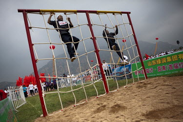 Competitors dressed as revolutionary militia climb a rope net in the obstacle course event of the Red Games. Held in Junan County, this sporting event is a nostalgic tribute to the communist era.