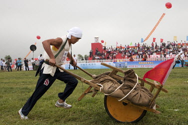 A competitor dressed as a revolutionary farmer pushes a wheel barrow on the 'battlefield' at the Red Games. Held in Junan County, this sporting event is a nostalgic tribute to the communist era.
