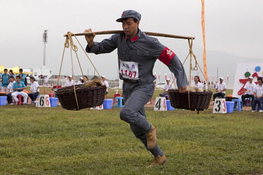 A competitor dressed in a PLA (People's Liberation Army) revolutionary era outfit runs in the 100m Shoulder-pole Race at the Red Games. Held in Junan County, this sporting event is a nostalgic tribute...