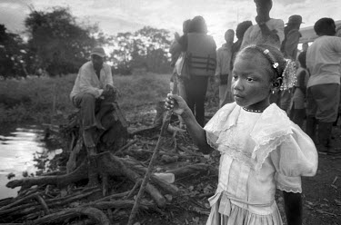A young girl stands by a river bank as newly arrived passengers, returning to Cacarica, disembark from a boat after crossing the Gulf of Uraba. They are to found a 'Peace Community', a settlement of p...